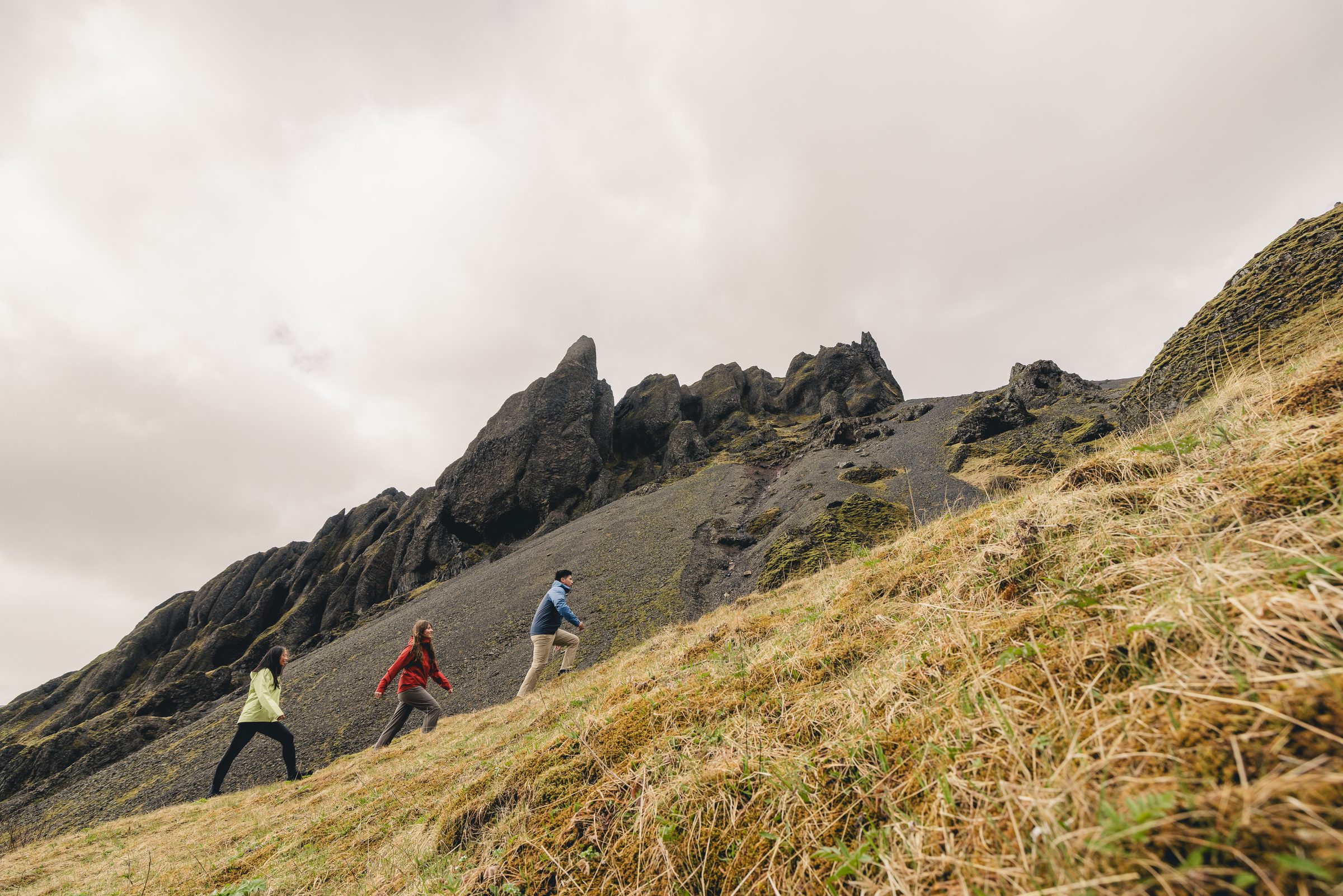 Two hikers in red and yellow Marmot jackets in front of a waterfall in Iceland