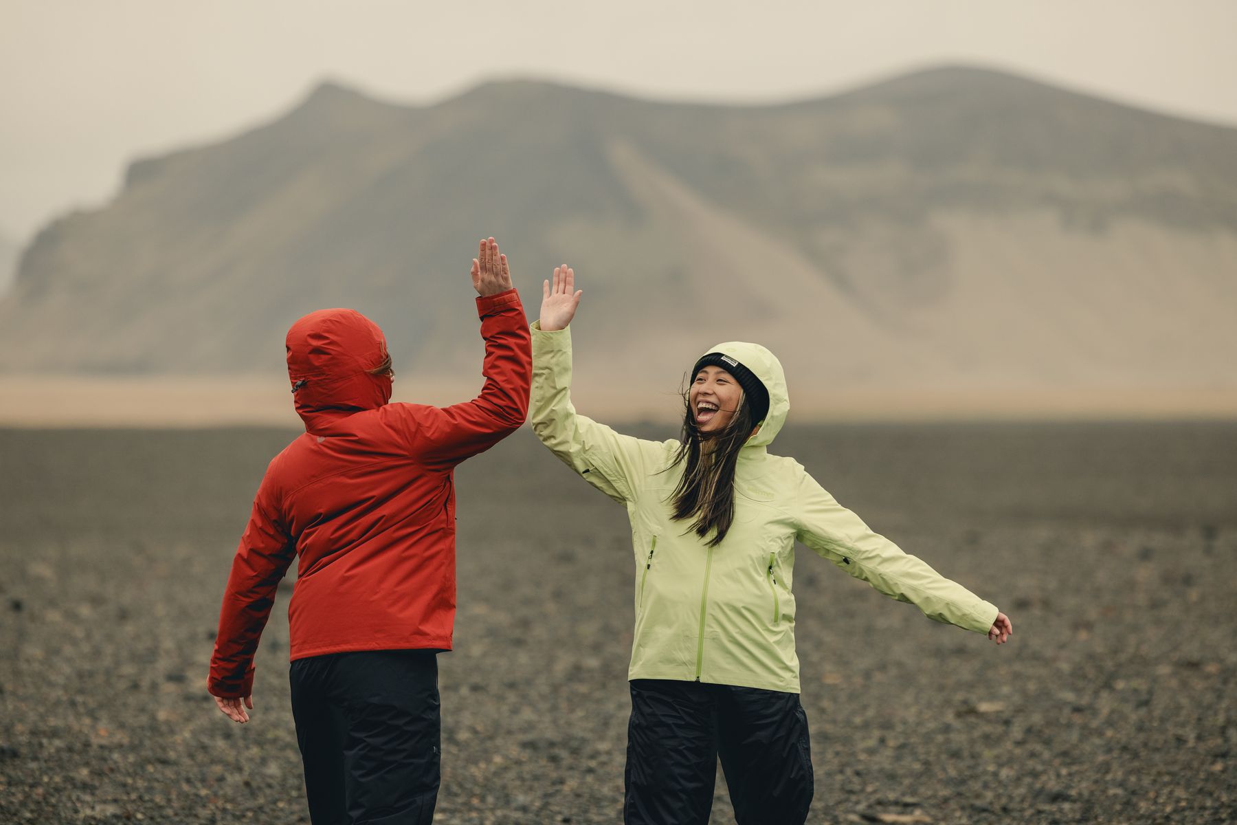 Two hikers high-fiving on a black sand plain in Iceland