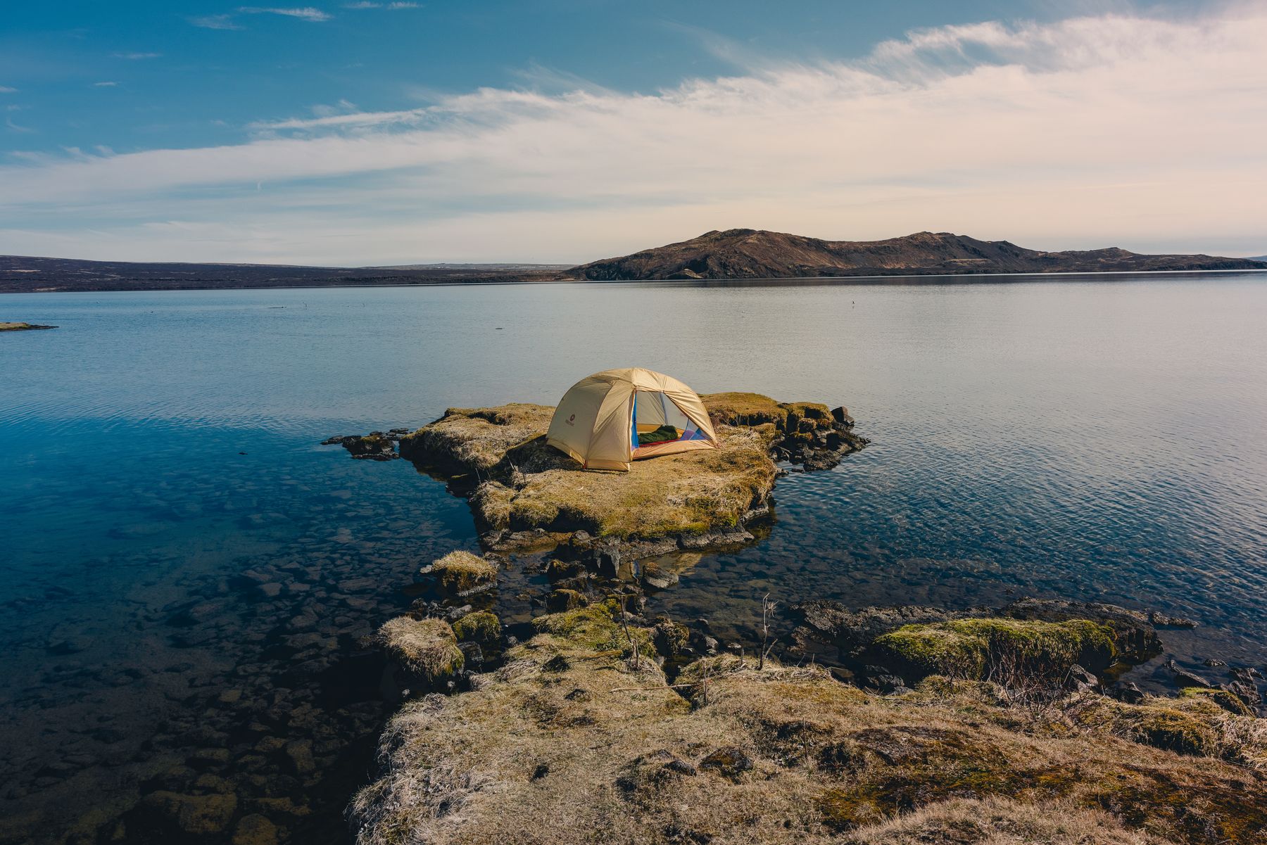 A Marmot tent on a rocky outcrop in a lake
