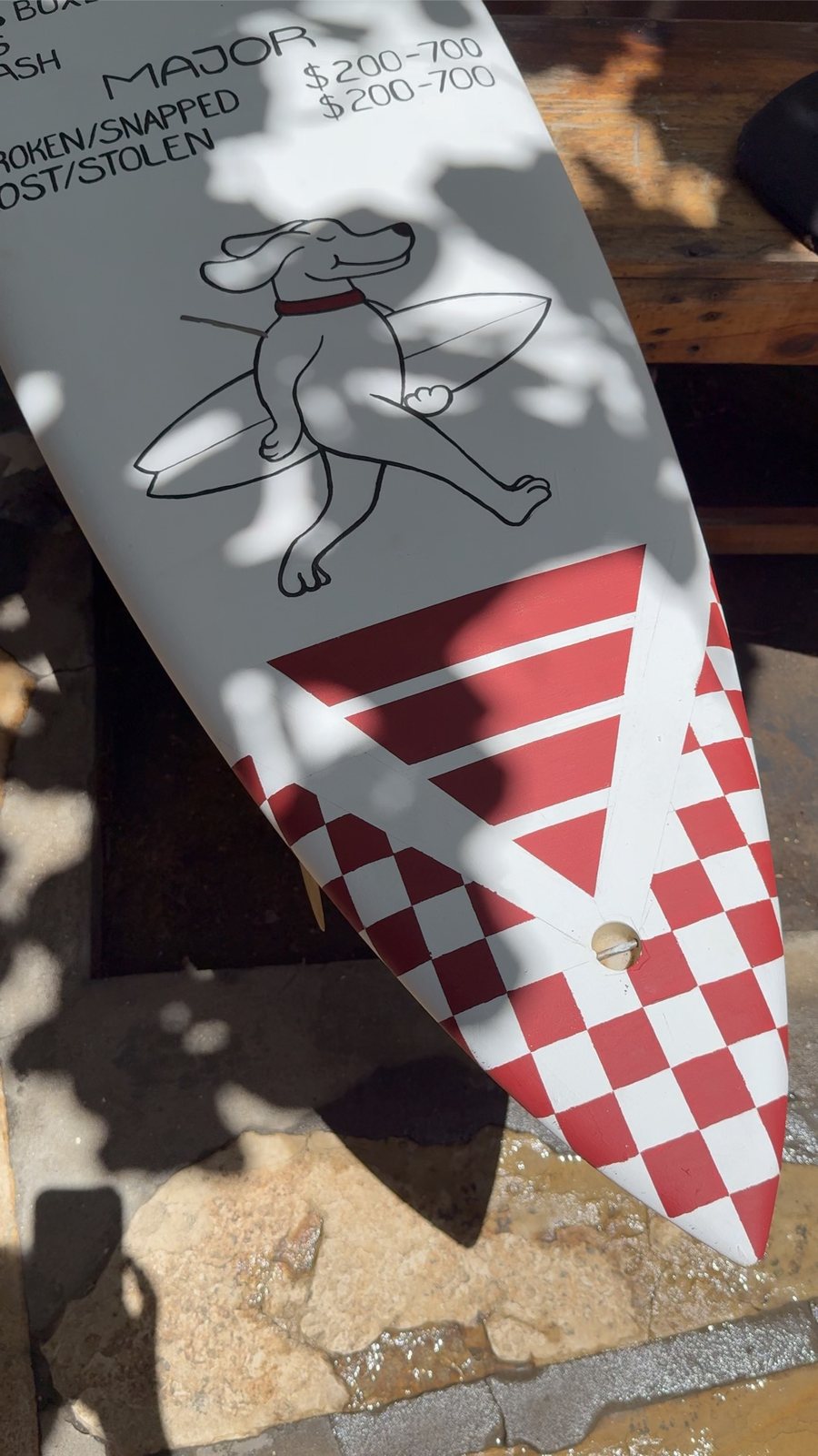 Tip of a surfboard with the surfing skeleton and checker flag