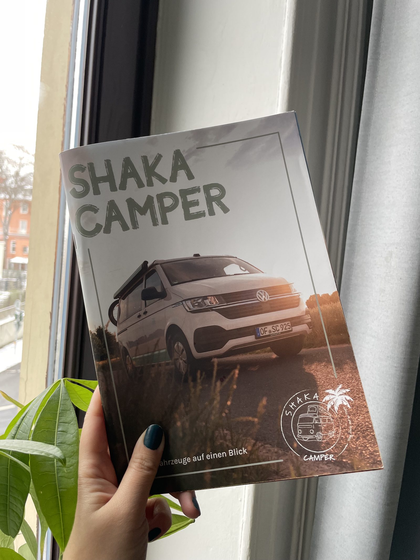 Printed Shaka Camper magazine held up by a window